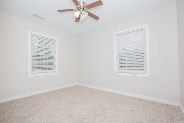 carpeted empty room featuring baseboards, visible vents, and a ceiling fan