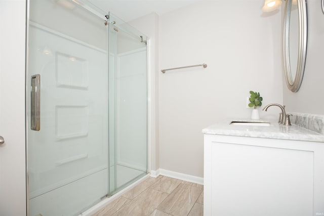 bathroom with a stall shower, baseboards, and vanity