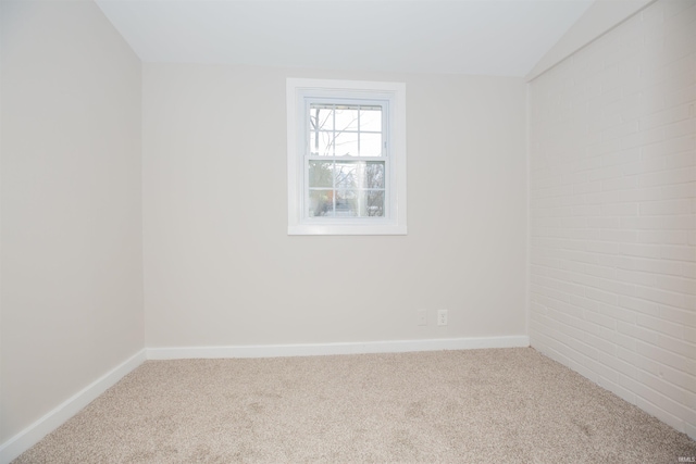 carpeted empty room featuring lofted ceiling and baseboards