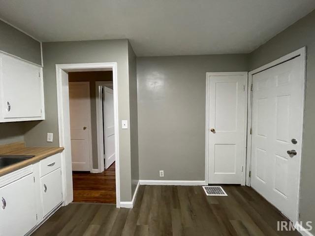 interior space featuring dark wood-style floors, visible vents, and baseboards