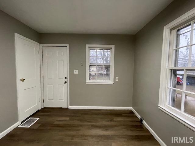 interior space with dark wood-style floors, visible vents, and baseboards