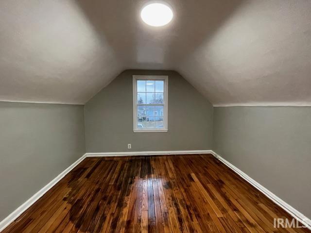 bonus room featuring vaulted ceiling, baseboards, and dark wood finished floors