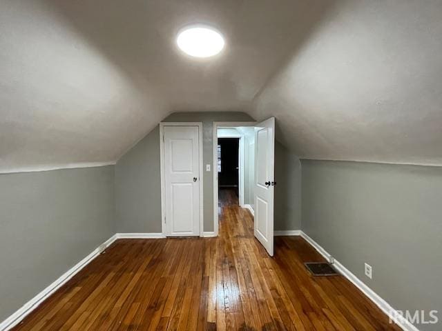 additional living space with visible vents, vaulted ceiling, baseboards, and hardwood / wood-style flooring