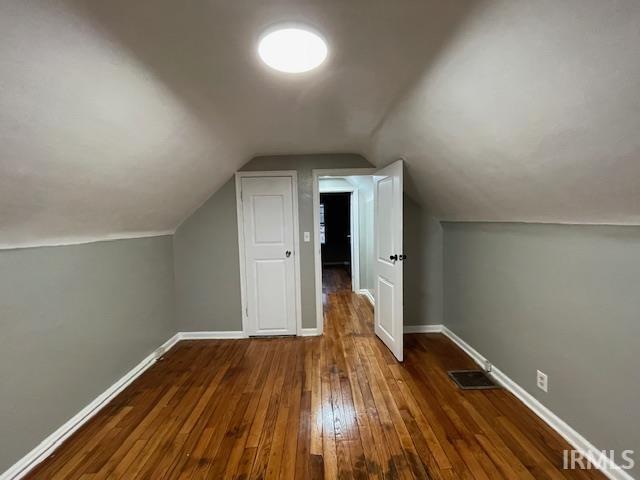 bonus room with vaulted ceiling, hardwood / wood-style floors, visible vents, and baseboards