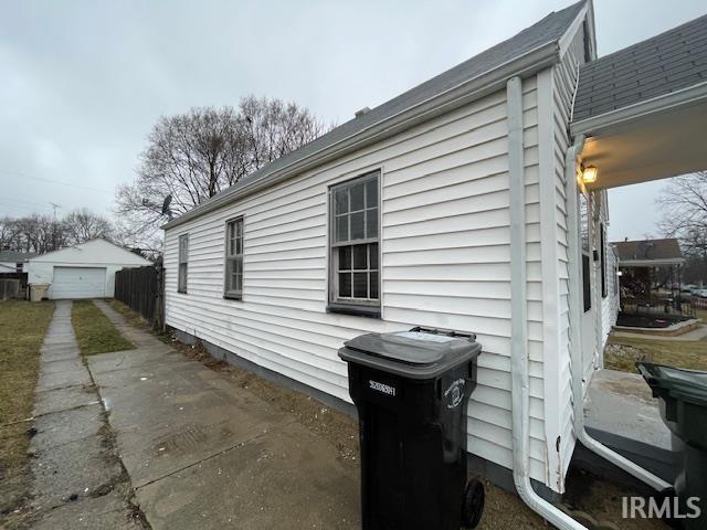 view of home's exterior with driveway, a detached garage, and an outdoor structure