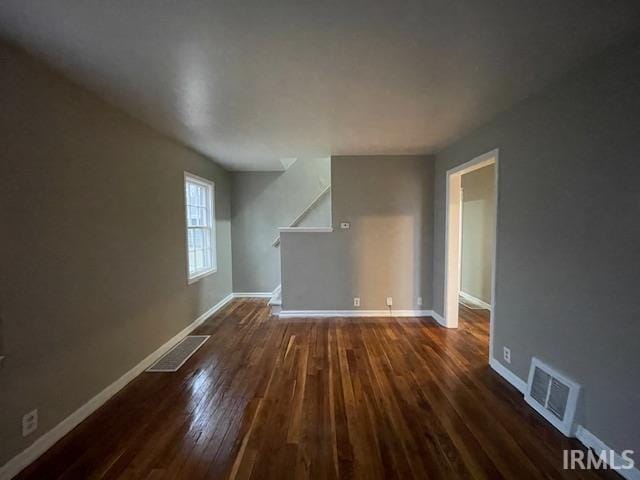 unfurnished living room featuring baseboards, visible vents, and dark wood-style flooring