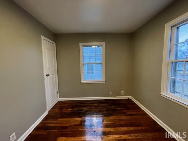 empty room with dark wood-style flooring and baseboards