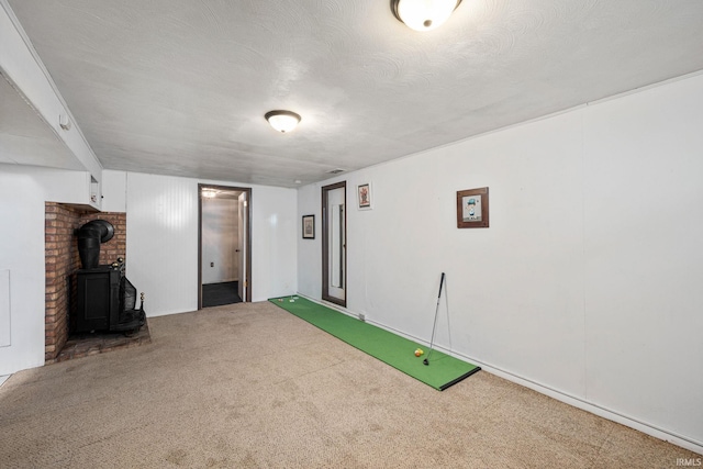 recreation room with a textured ceiling, golf simulator, carpet flooring, and a wood stove