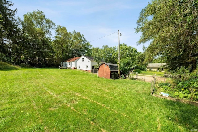 view of yard with a garden, a shed, fence, and an outbuilding