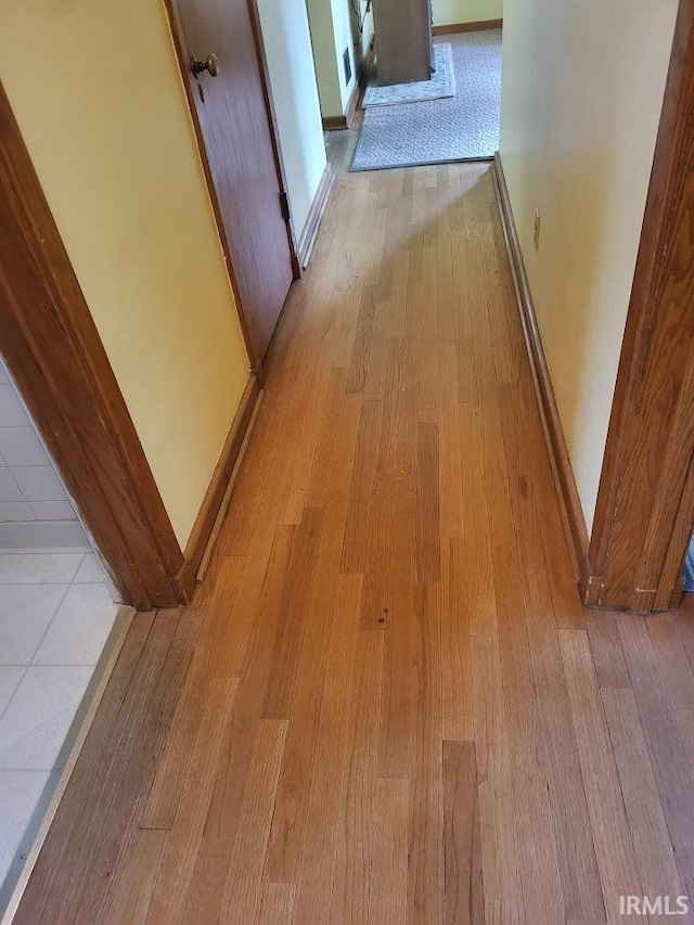 hall with light wood-type flooring and baseboards