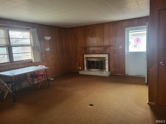 unfurnished living room featuring carpet floors, wooden walls, and a fireplace