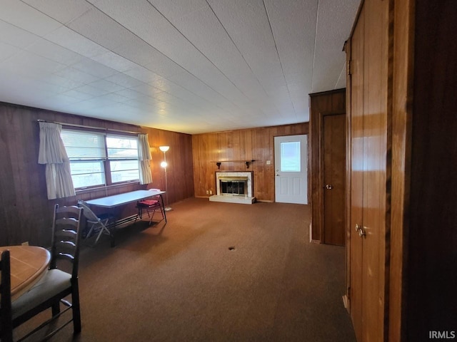 carpeted living room with wooden walls and a glass covered fireplace