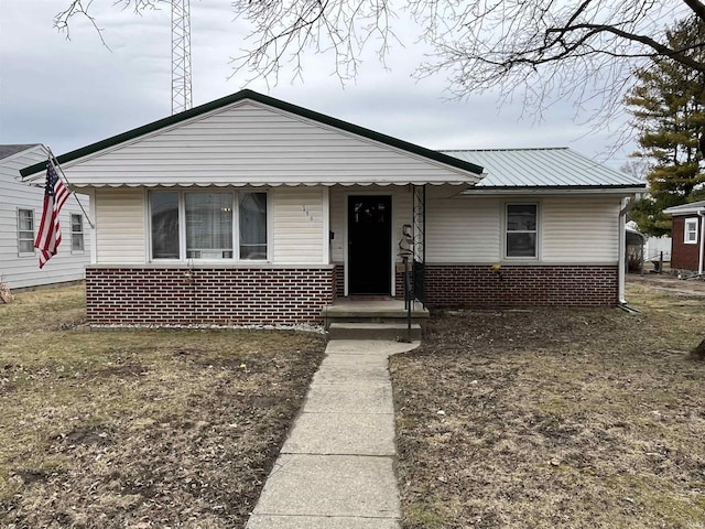 bungalow-style house with metal roof and brick siding