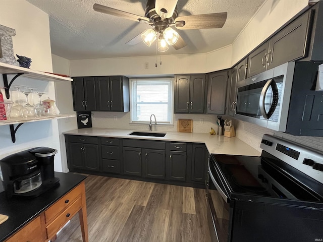 kitchen featuring dark wood finished floors, light countertops, appliances with stainless steel finishes, a sink, and a textured ceiling