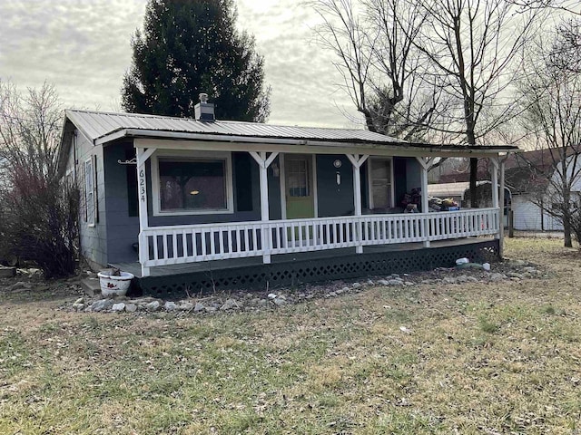 view of front of property featuring metal roof, a porch, and a chimney