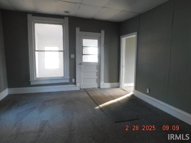 carpeted empty room with a paneled ceiling and baseboards