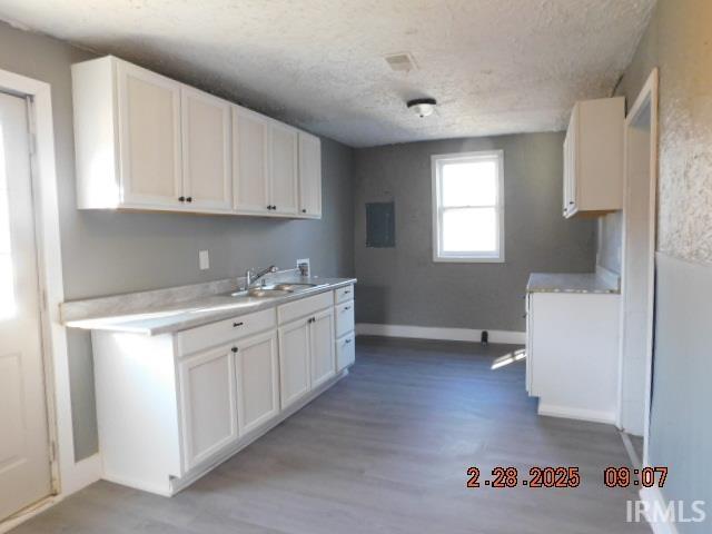 kitchen with white cabinetry, light countertops, a sink, and wood finished floors