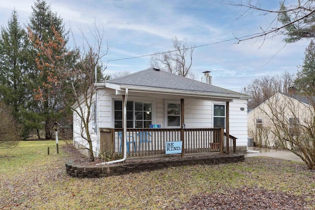 bungalow featuring a porch, a front yard, and a shingled roof