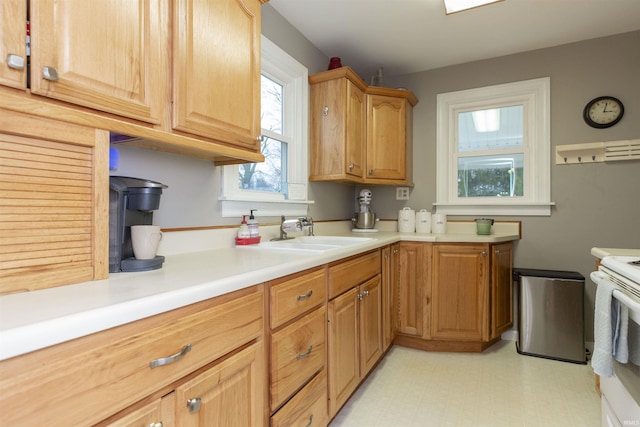 kitchen with light countertops, a sink, electric range, and light floors