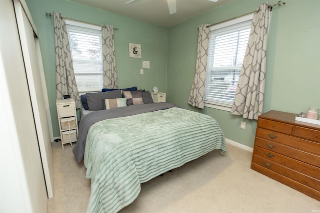 bedroom with light carpet, multiple windows, baseboards, and a ceiling fan