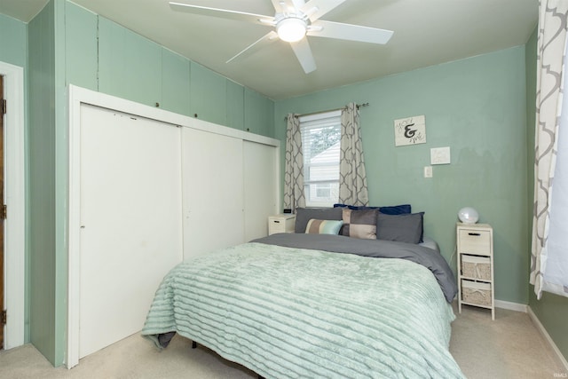 bedroom featuring light carpet, a ceiling fan, and a closet