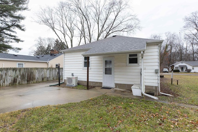 rear view of house with a shingled roof, a patio area, fence, a yard, and ac unit