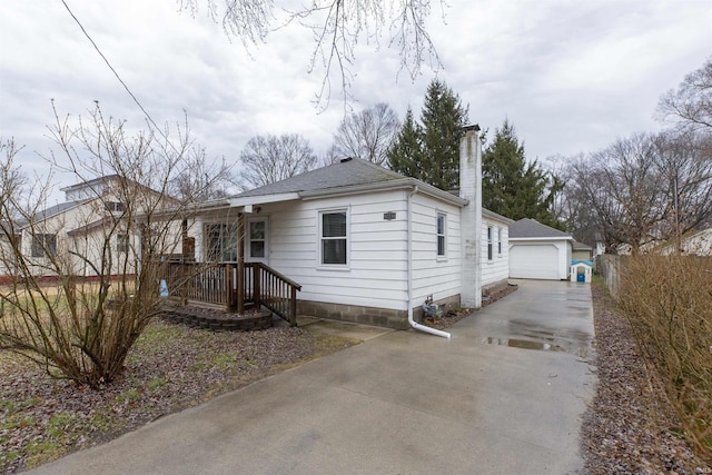 view of front of house featuring an outbuilding, a chimney, a shingled roof, fence, and a garage