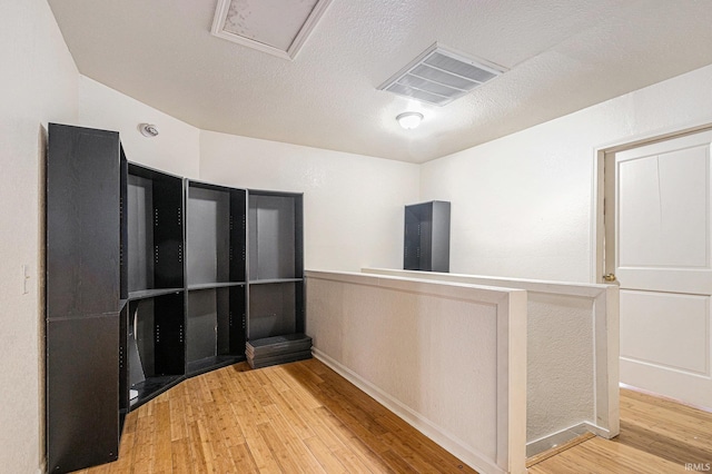 unfurnished room featuring a textured ceiling, wood finished floors, and visible vents