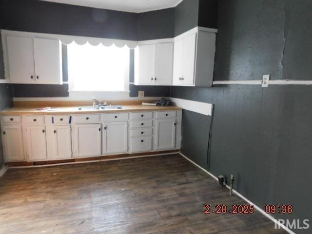 kitchen featuring white cabinets, dark wood-style flooring, a sink, and light countertops