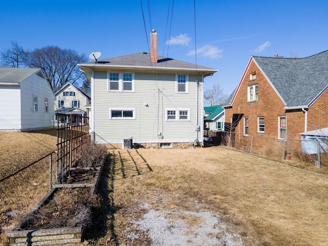 back of property featuring a yard, a chimney, and fence