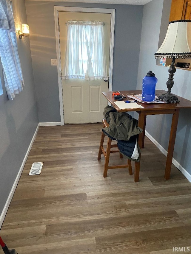 entryway with baseboards, visible vents, and wood finished floors