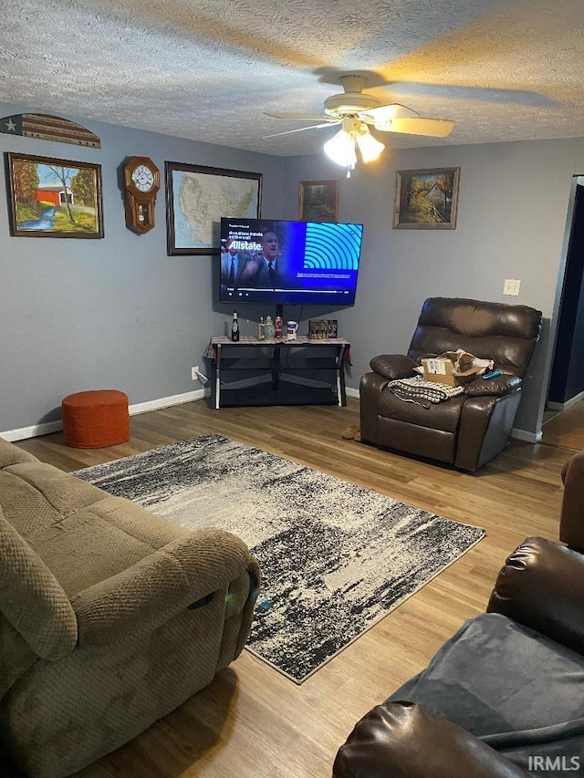 living room with a textured ceiling, wood finished floors, a ceiling fan, and baseboards