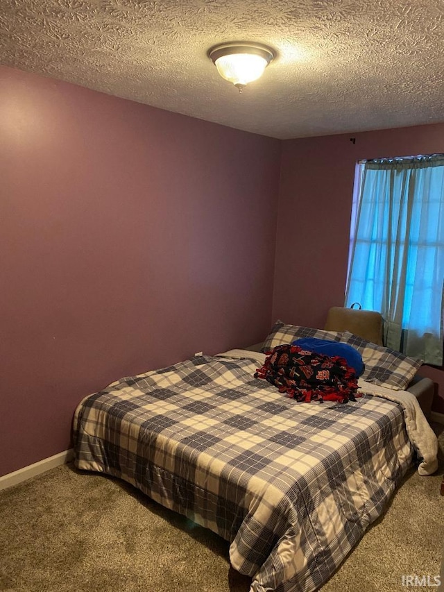 carpeted bedroom with a textured ceiling and baseboards