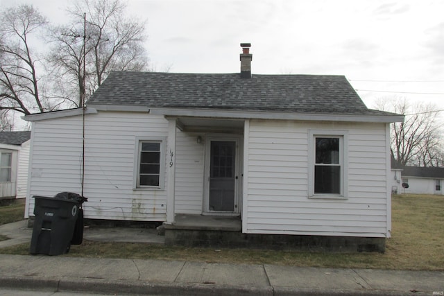 back of property featuring a shingled roof and a lawn