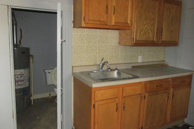 kitchen featuring brown cabinetry, water heater, backsplash, and a sink