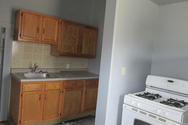 kitchen featuring a sink, brown cabinetry, decorative backsplash, and gas range gas stove