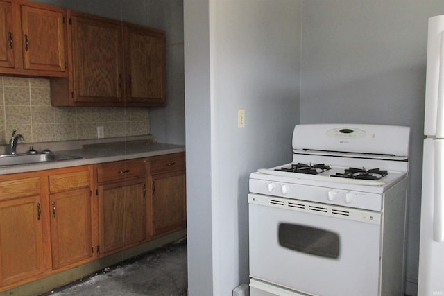 kitchen with white appliances, brown cabinetry, a sink, and tasteful backsplash