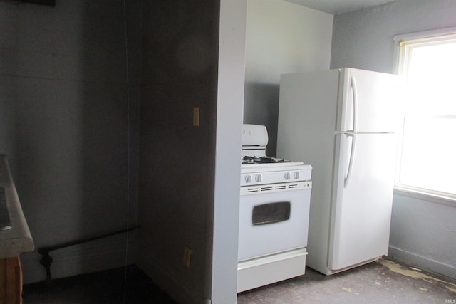 kitchen with white appliances and concrete flooring