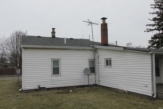 back of property featuring roof with shingles and a lawn