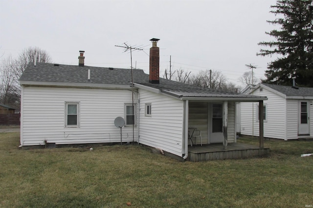 rear view of property featuring metal roof, roof with shingles, a lawn, and an outdoor structure