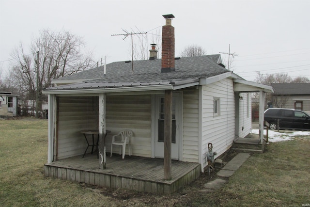 back of property with a shingled roof, a lawn, and a chimney