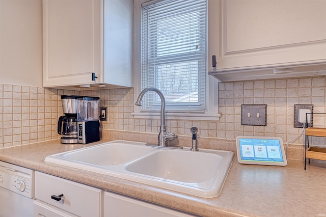 kitchen with white cabinets, white dishwasher, light countertops, and a sink