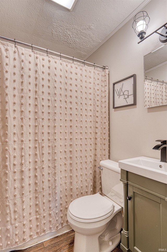 full bathroom featuring a textured ceiling, toilet, wood finished floors, vanity, and ornamental molding