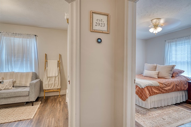 bedroom with a textured ceiling, ceiling fan, and wood finished floors