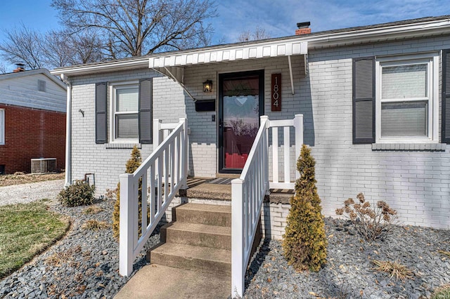 entrance to property featuring central AC, brick siding, and a chimney