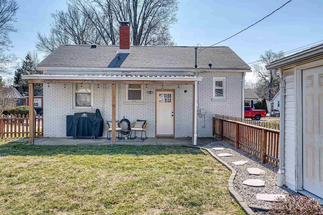 back of house featuring a patio area, a yard, a chimney, and brick siding