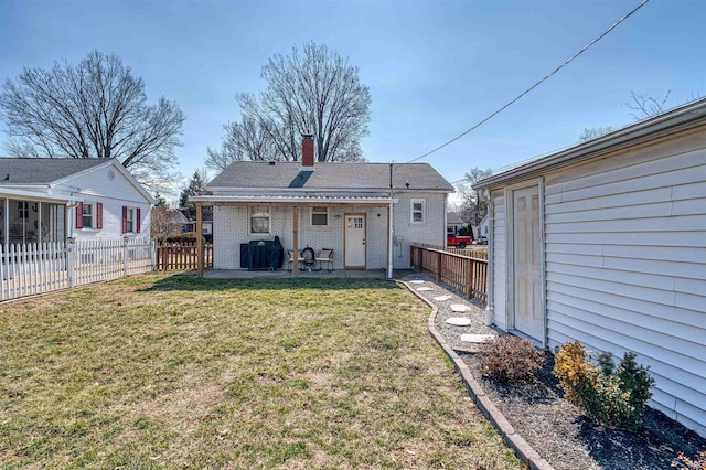 back of property with brick siding, a chimney, a lawn, a patio area, and a fenced backyard