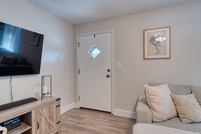 entryway featuring baseboards, a textured ceiling, and light wood finished floors