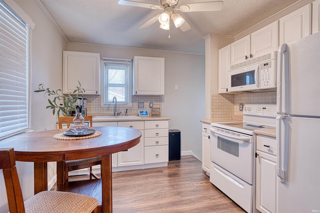 kitchen with white appliances, light wood finished floors, light countertops, white cabinetry, and a sink