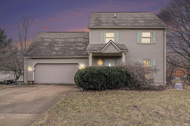 traditional-style house featuring concrete driveway, a front lawn, an attached garage, and a shingled roof